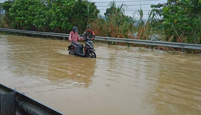 Jalan Putus Diterjang Banjir, Danramil 1307-11/Pamona Selatan Bantu Sebrangkan Warga Yang Melintas